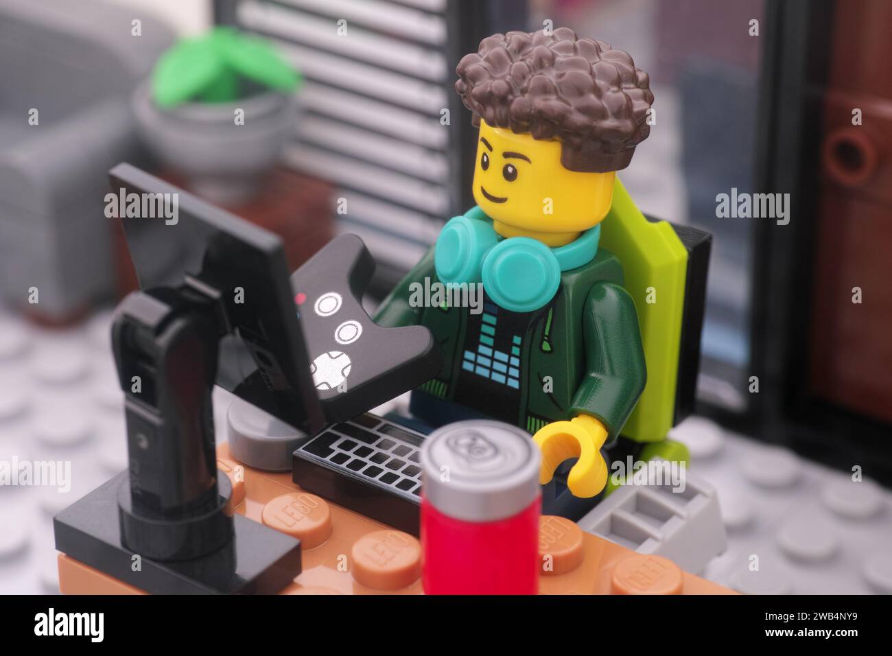 Tambov, Federazione Russa - 8 gennaio 2024 Una minifigura di un giocatore di videogiochi Lego con un gamepad seduto su una sedia da gioco e con cui gioca ai videogiochi Foto Stock