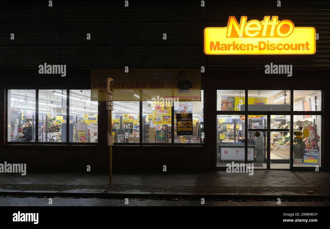 Berlino, Germania, 20 dicembre 2023, area d'ingresso del supermercato netto a Sklalitzer Strasse di notte con logo illuminato e vista sulla vendita Foto Stock
