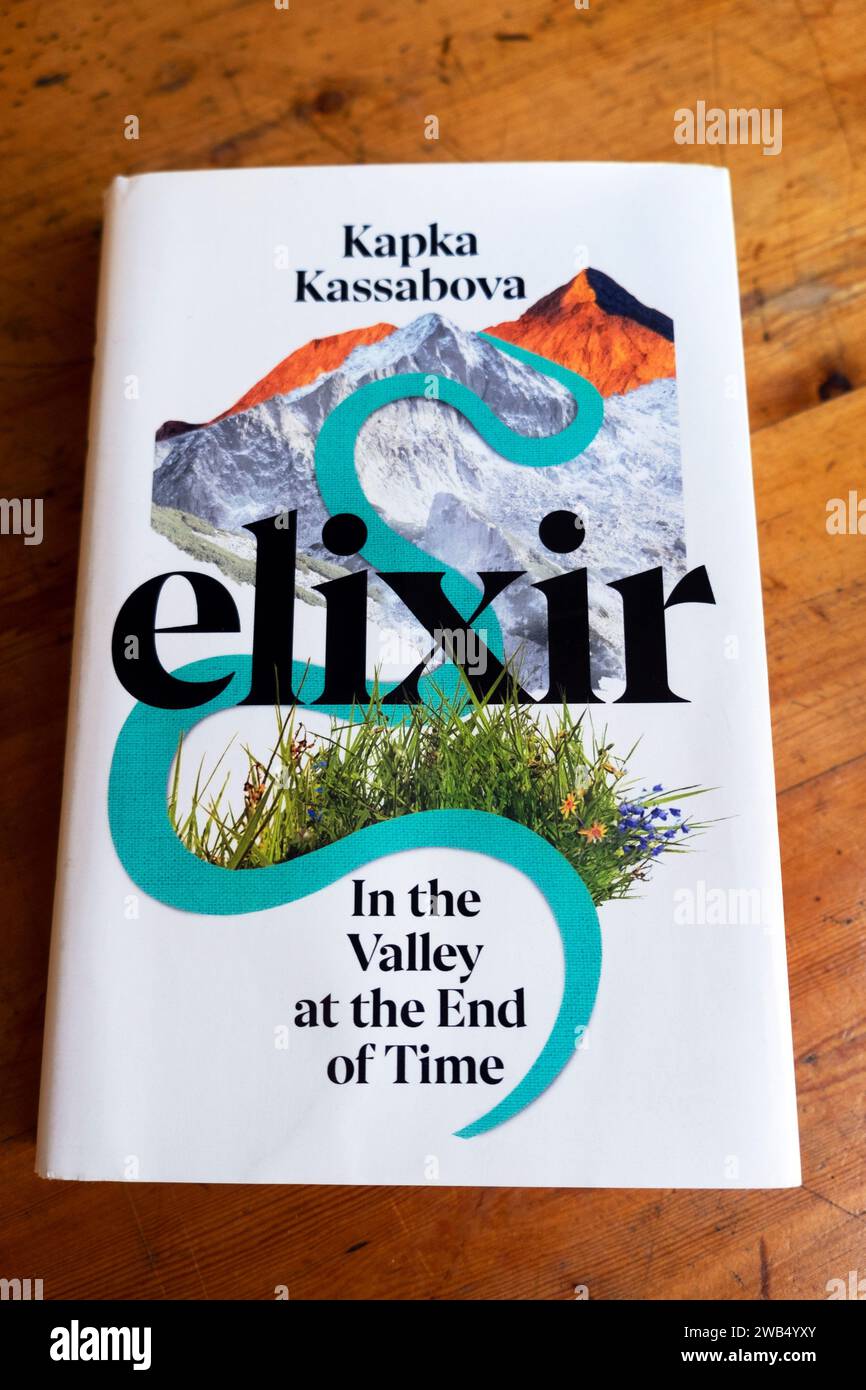 "ELIXIR in the Valley at the End of Time" pubblicato nel 2023, copertina di un libro della scrittrice bulgara Kapka Kassabova su un tavolo di legno KATHY DEWITT Foto Stock
