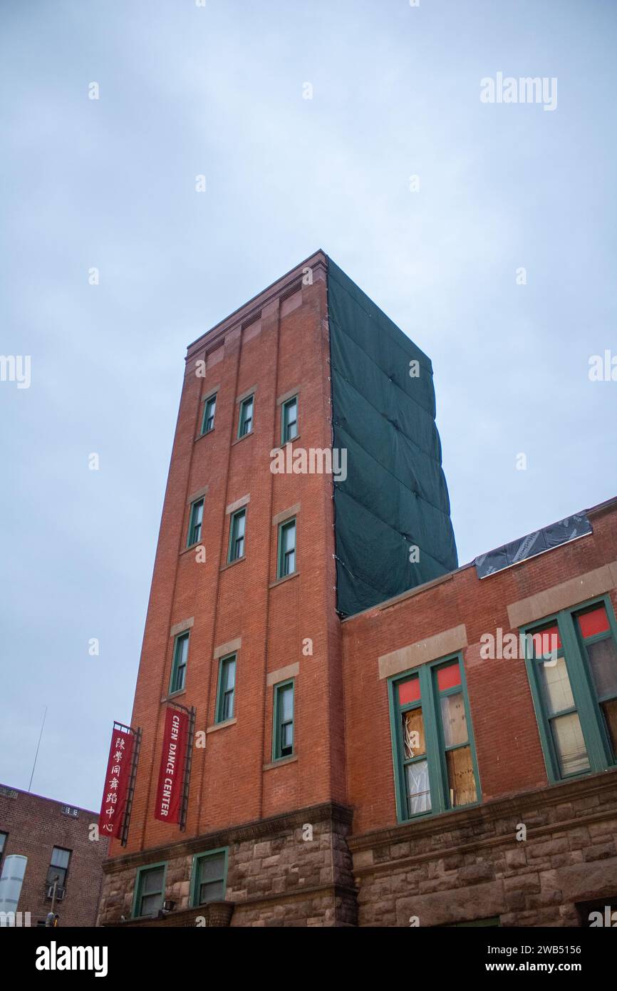 Un edificio in mattoni rossi con finestre verdi si trova nel mezzo di una vivace metropoli urbana Foto Stock