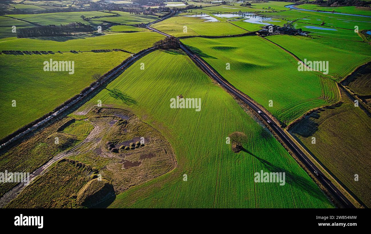 Vista aerea di un treno che passa attraverso i vivaci campi verdi con un cielo blu chiaro sopra la testa. Foto Stock