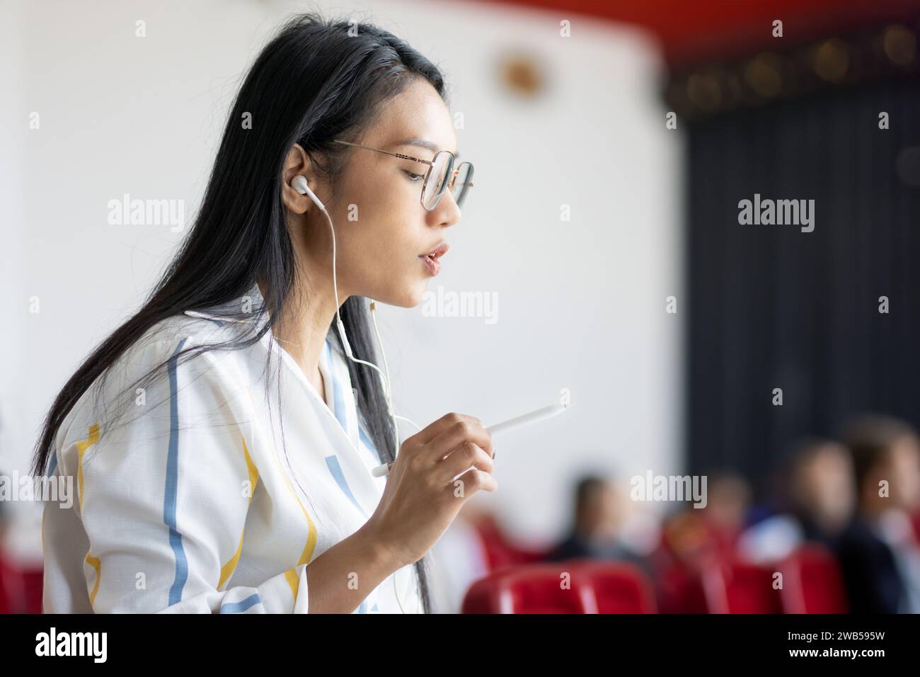 Una donna sta parlando in una sala conferenze con persone non riconoscibili sullo sfondo Foto Stock