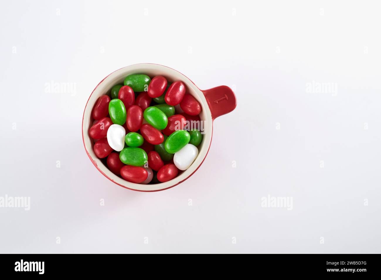 Stendere in piano le gelatine rosse, verdi e bianche in un dosatore rosso su sfondo bianco Foto Stock
