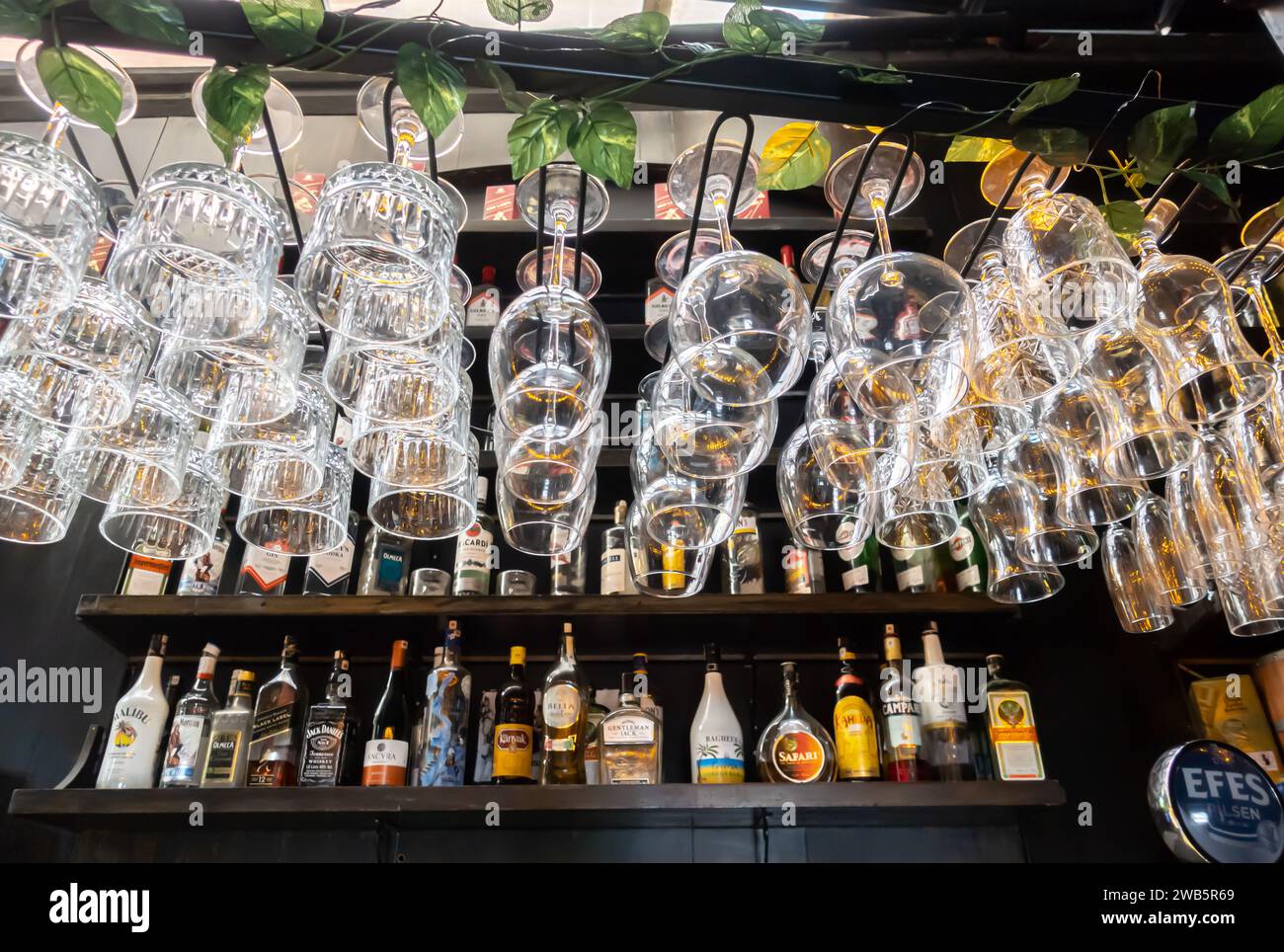 Bicchieri da vino e liquori appesi al banco del bar Foto Stock
