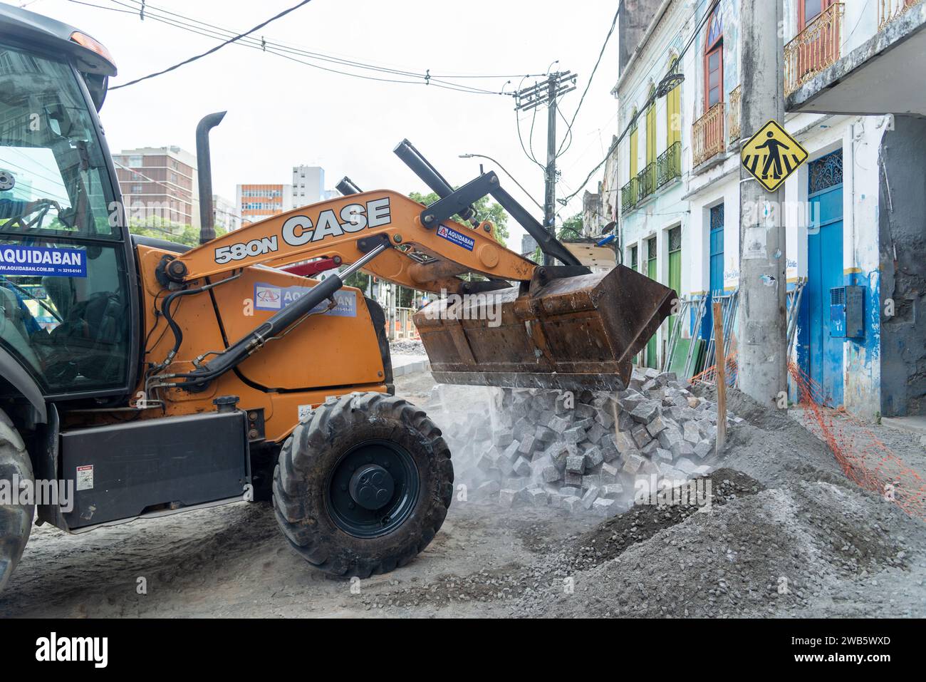 Salvador, Bahia, Brasile - 5 gennaio 2024: Trattore retroescavatore che trasporta pietre nei lavori di ricostruzione in via Conceicao da Praia nello spot Foto Stock