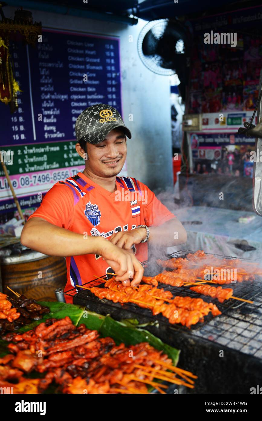 Un uomo tailandese che grigia pollo in un piccolo Street food su Soi Naradhiwas Rajanagarindra a Bangkok, Thailandia. Foto Stock