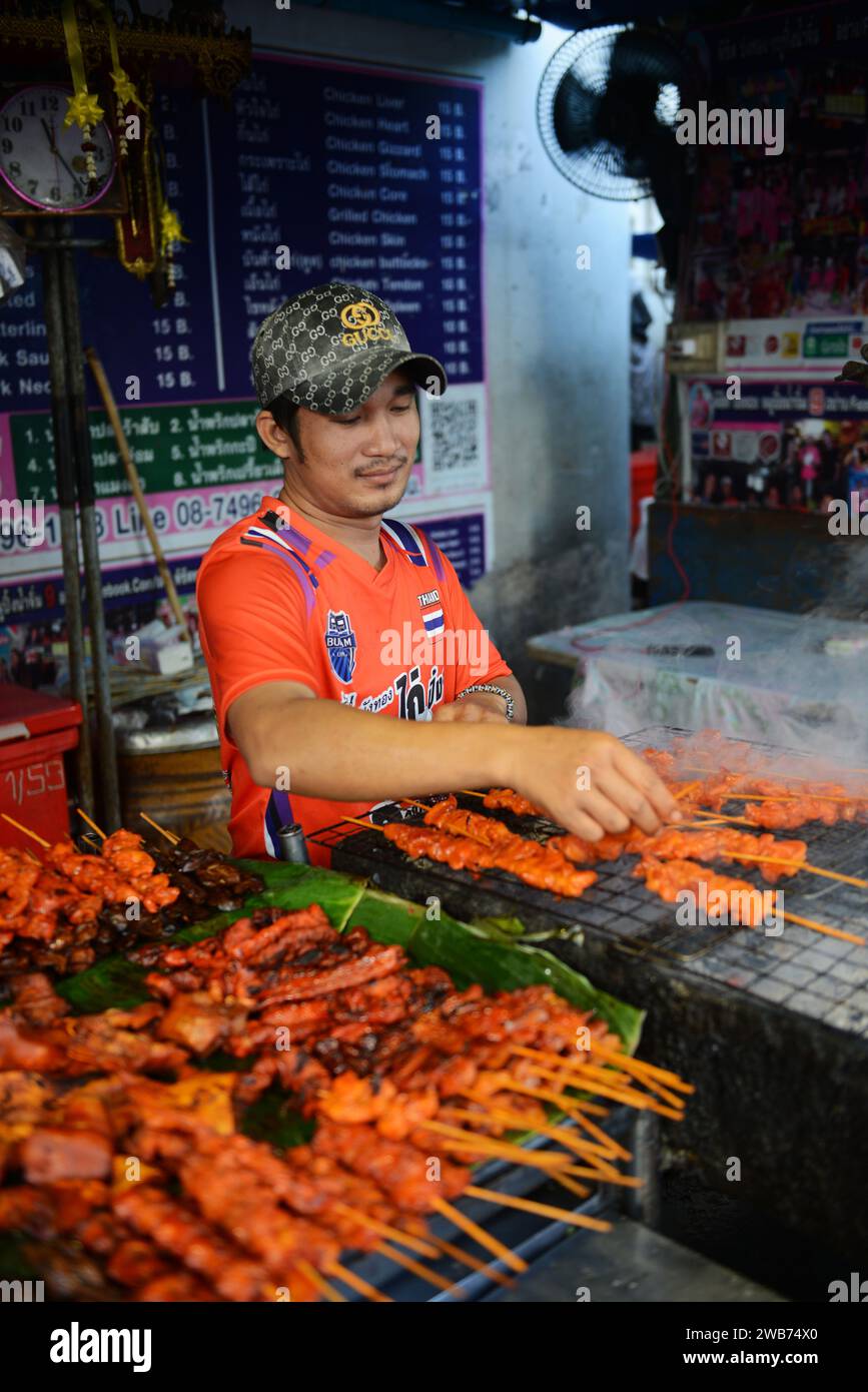 Un uomo tailandese che grigia pollo in un piccolo Street food su Soi Naradhiwas Rajanagarindra a Bangkok, Thailandia. Foto Stock
