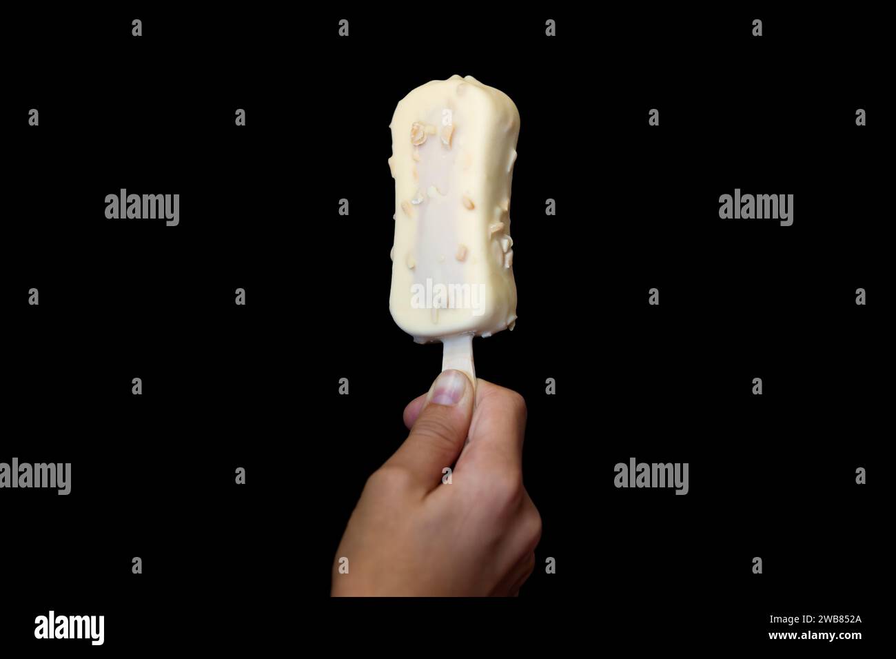 Estate, vacanze, gelato. La mano tiene un gelato morbido in una menta di cioccolato . Messa a fuoco selettiva, rumore. Su sfondo nero, primo piano. Una bambina Foto Stock