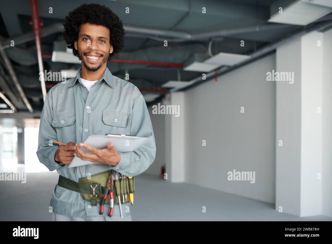 Ritratto di un lavoratore edile sorridente che compila il modulo sugli appunti Foto Stock