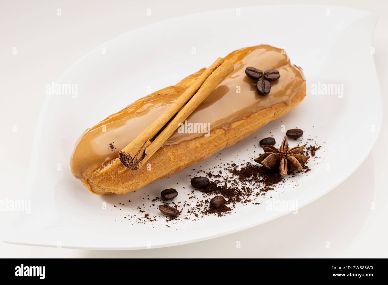 Un delizioso dessert all'eclair al gusto di caffè decorato con chicchi di caffè e bastoncino di cannella Foto Stock