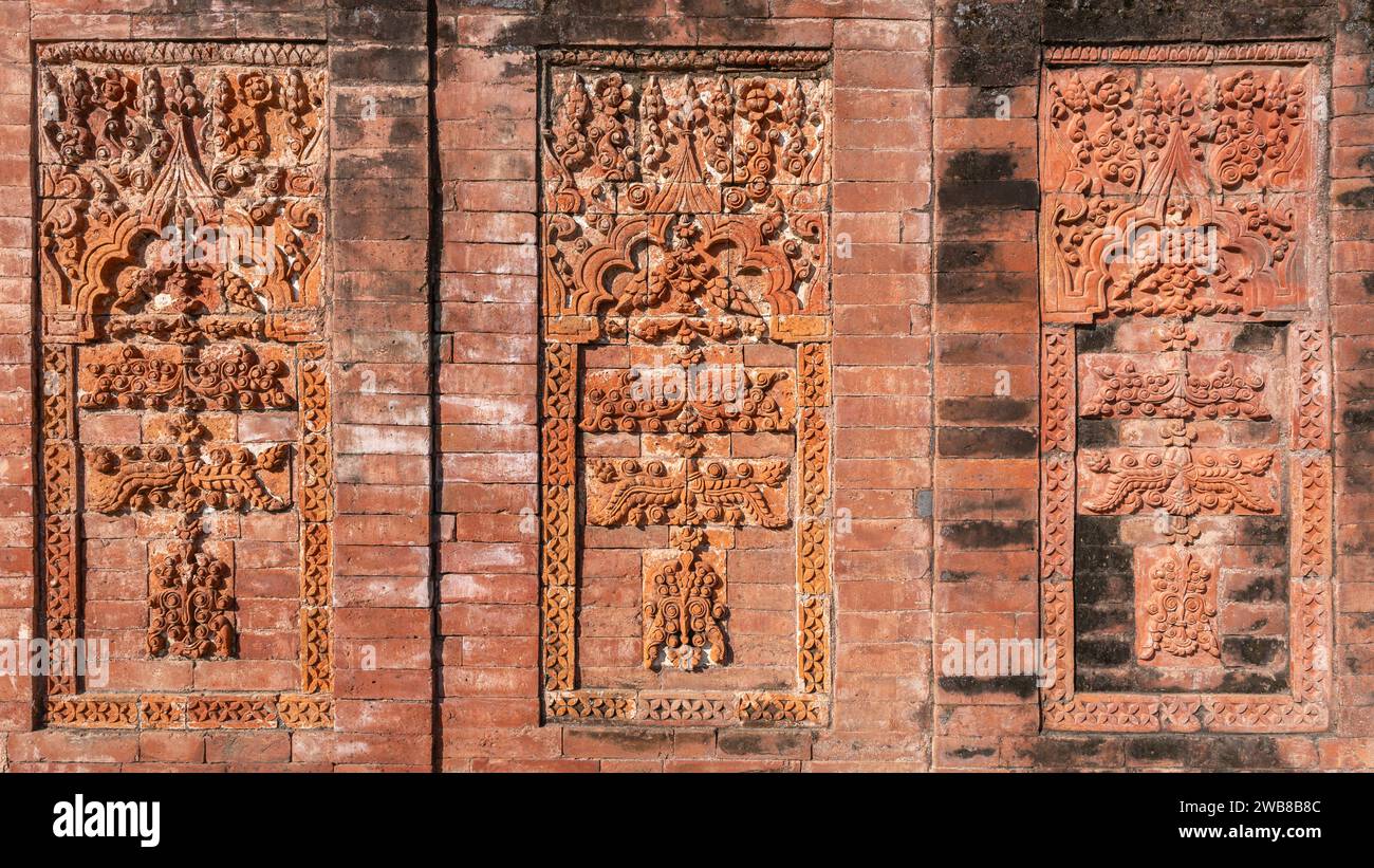 Vista ravvicinata dell'antico decor in terracotta con motivi floreali e geometrici sulle pareti esterne in mattoni della moschea di Sura, Ghoraghat, Dinajpur, Bangladesh Foto Stock