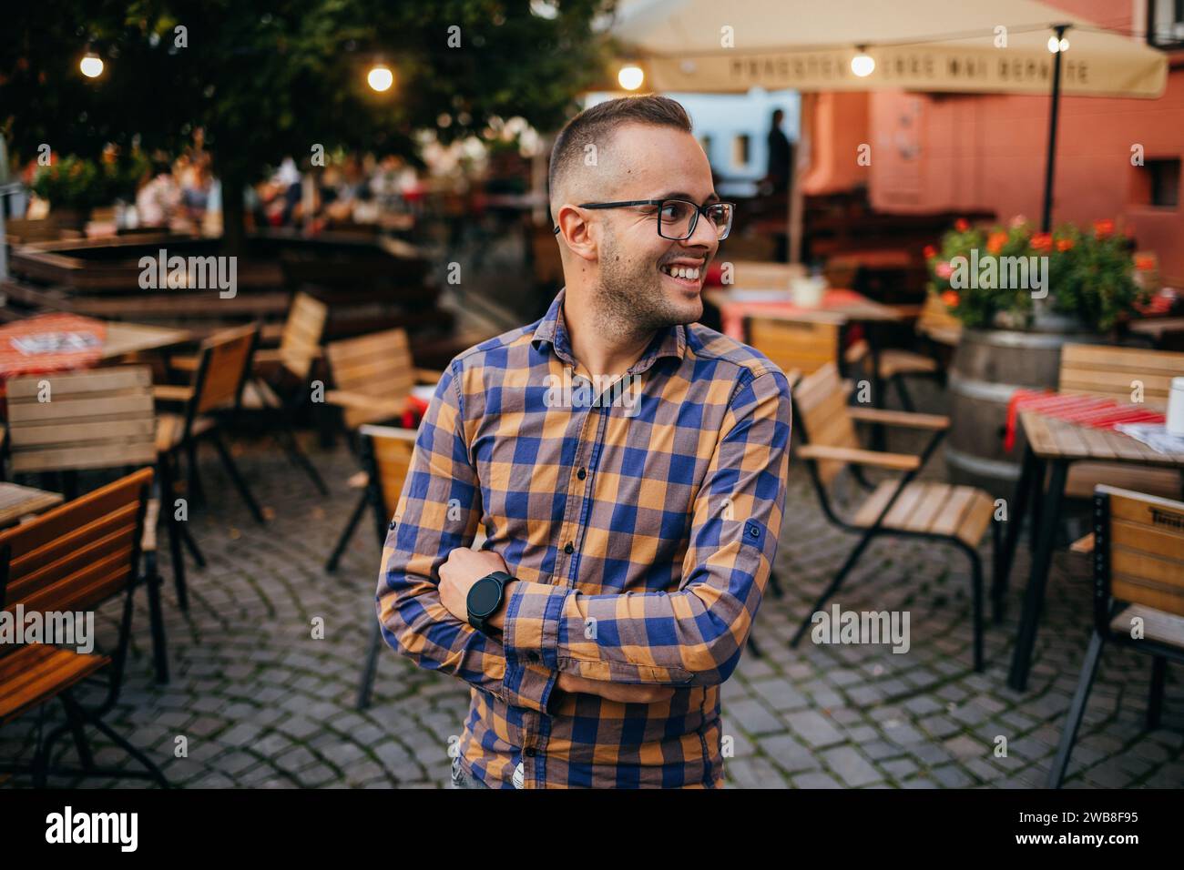 Giovane uomo d'affari in camicia sorridente nella terrazza di un ristorante Foto Stock