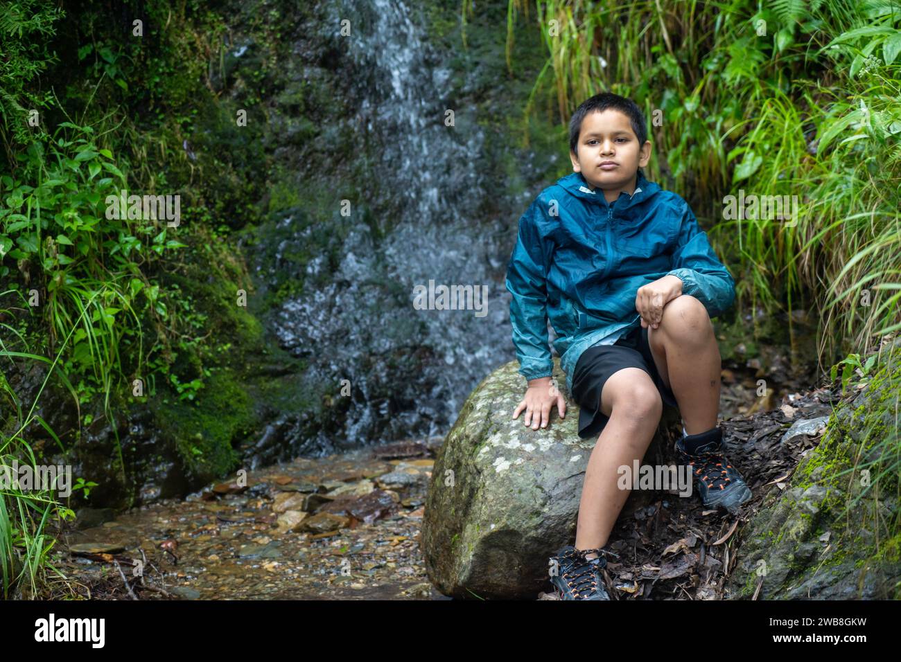 Nel cuore della natura, un ragazzo indiano seduto su una pietra senza tempo. Foto Stock