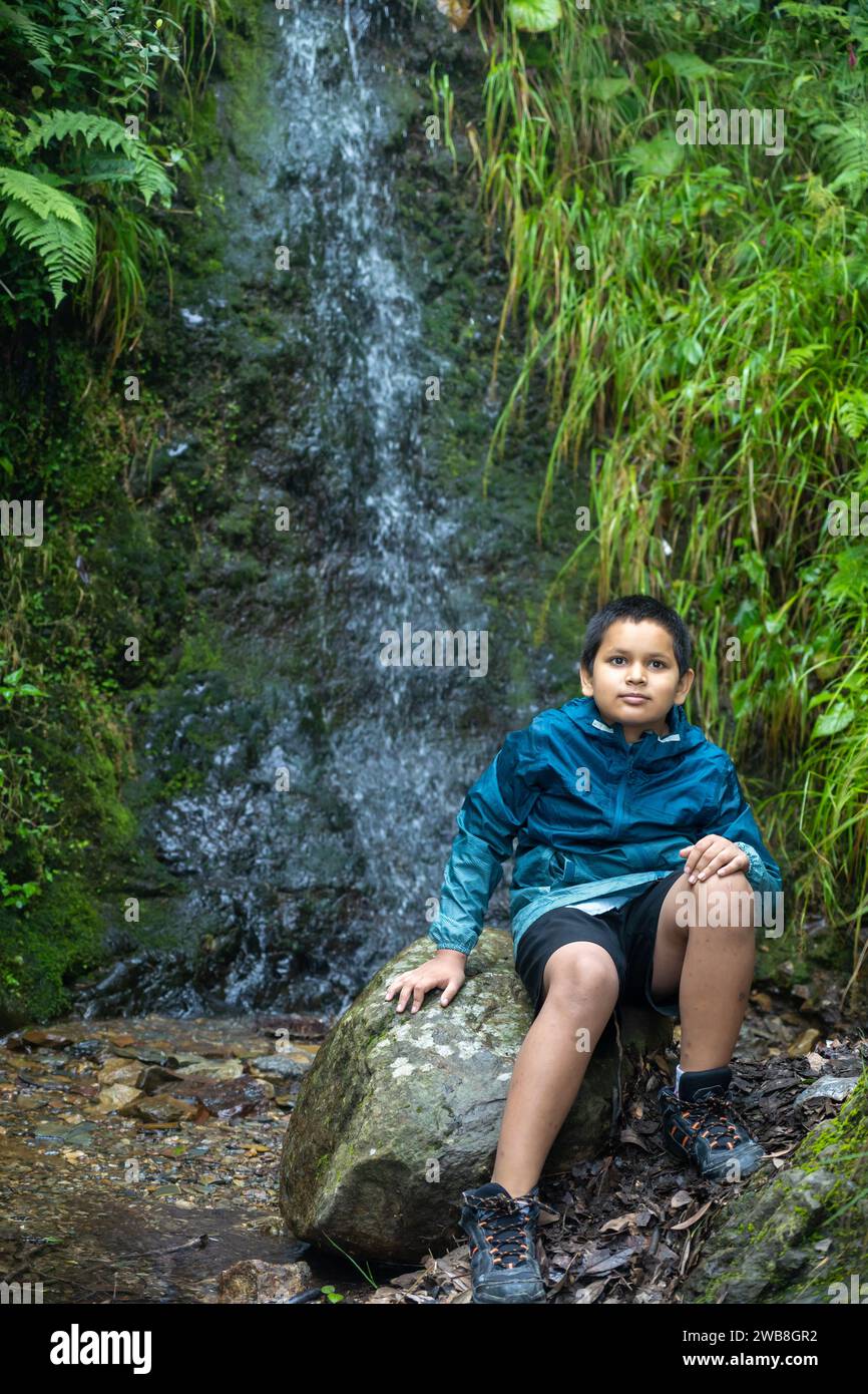 Nel cuore della natura, un ragazzo indiano seduto su una pietra senza tempo. Foto Stock