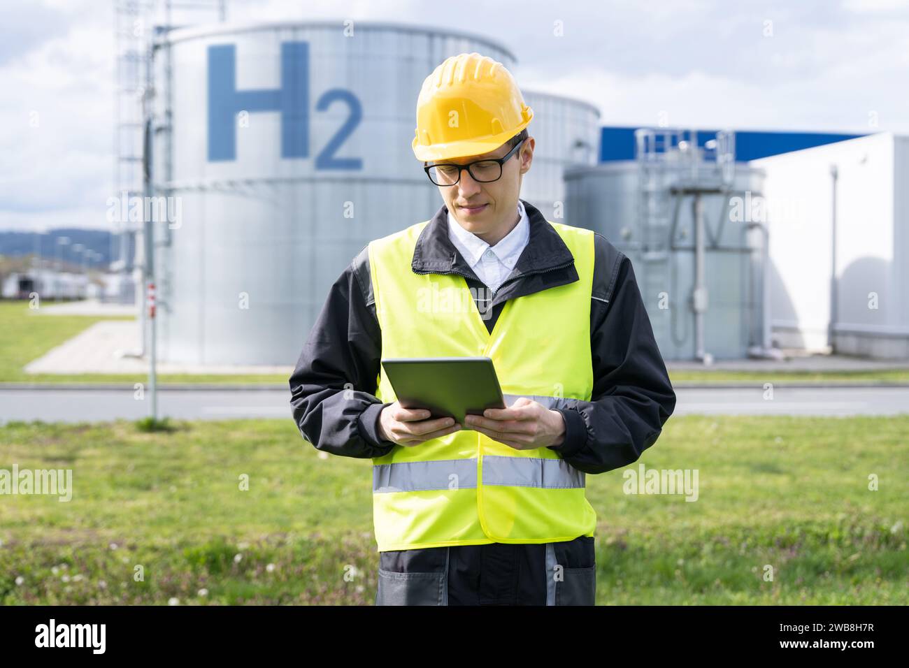 Ingegnere con computer tablet su uno sfondo di fabbrica di idrogeno. Foto Stock