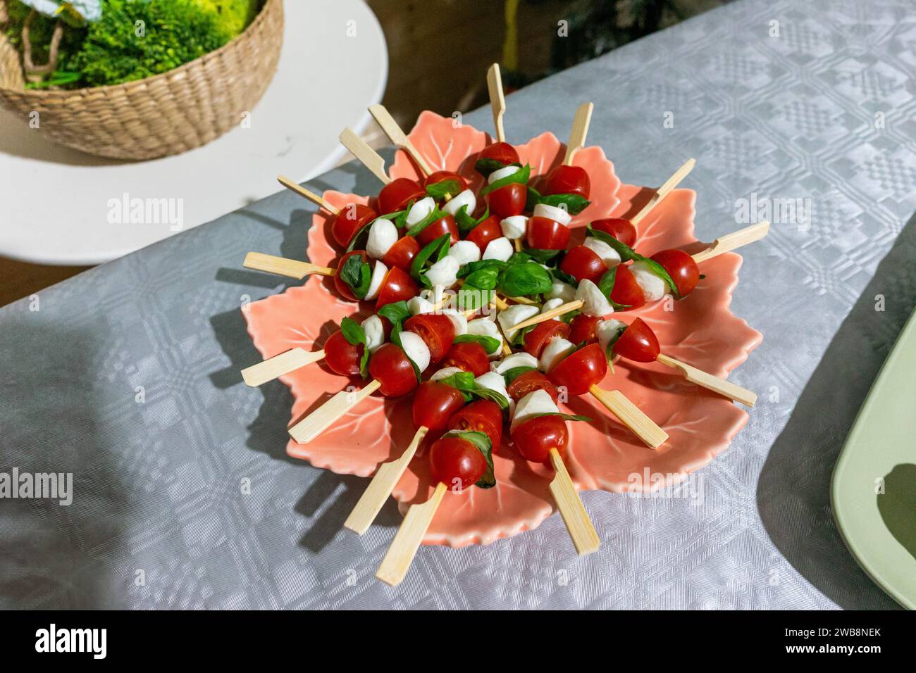 Vivaci spiedini di pomodoro ciliegia con formaggio fresco e basilico, un'aggiunta squisita a qualsiasi riunione festiva. Foto Stock