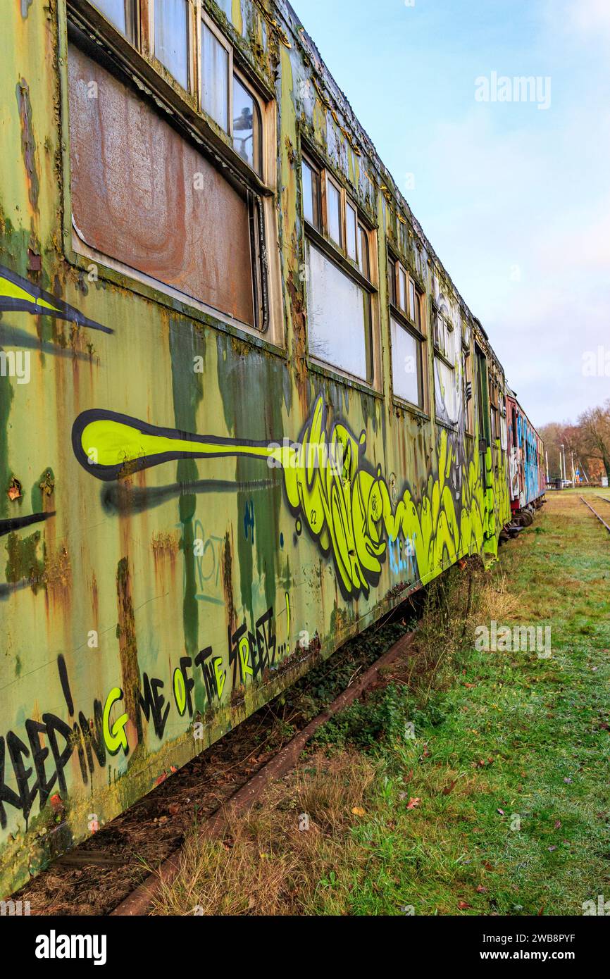 AS, Limburgo, Belgio. 17 dicembre 2023. Prospettiva laterale di una vecchia autovettura verde verniciata con graffiti, metallo corroso e arrugginito, in disuso Foto Stock