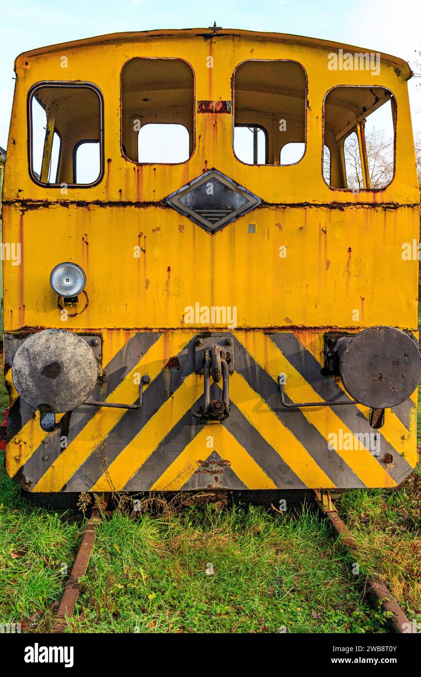 Vista frontale della vecchia cabina di controllo ferroviaria in rovina gialla smantellata, finestrini senza vetri e fermi di accoppiamento, binari in disuso presso la vecchia stazione ferroviaria, arrugginiti Foto Stock