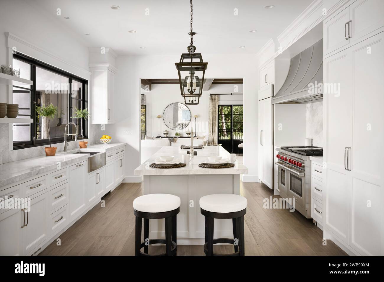 Una cucina moderna con armadietti bianchi e ripiani in marmo, impreziosita da un elegante sgabello nero per un look contemporaneo Foto Stock