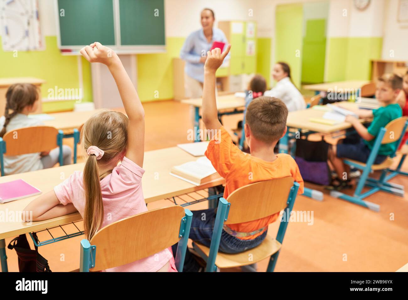 Vista posteriore dei bambini che alzano la mano durante la sessione QNA in classe Foto Stock
