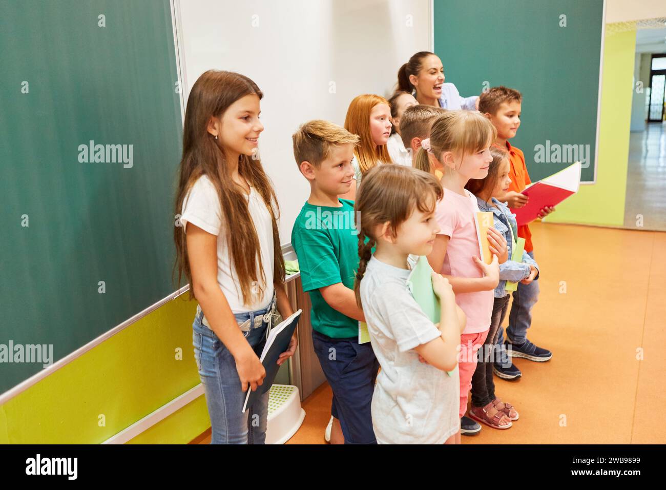 Gruppo di studenti sorridenti, maschi e femmine, che tengono insieme libri in classe Foto Stock