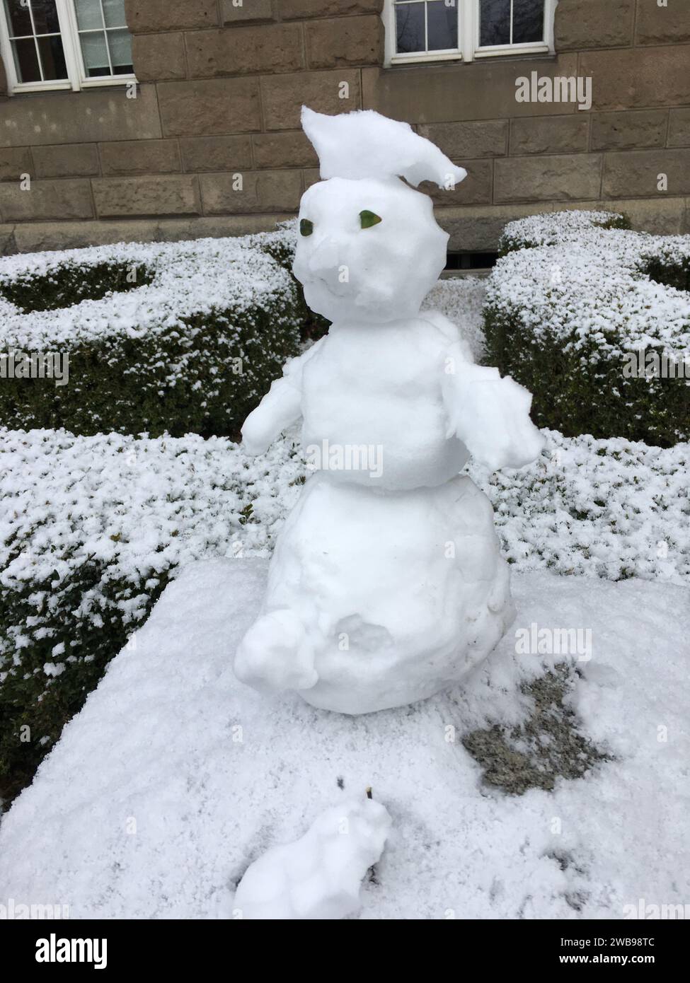Un piccolo pupazzo di neve è migliorato su un palo di pietra. Versione mini. Inverno in Polonia. Foto Stock
