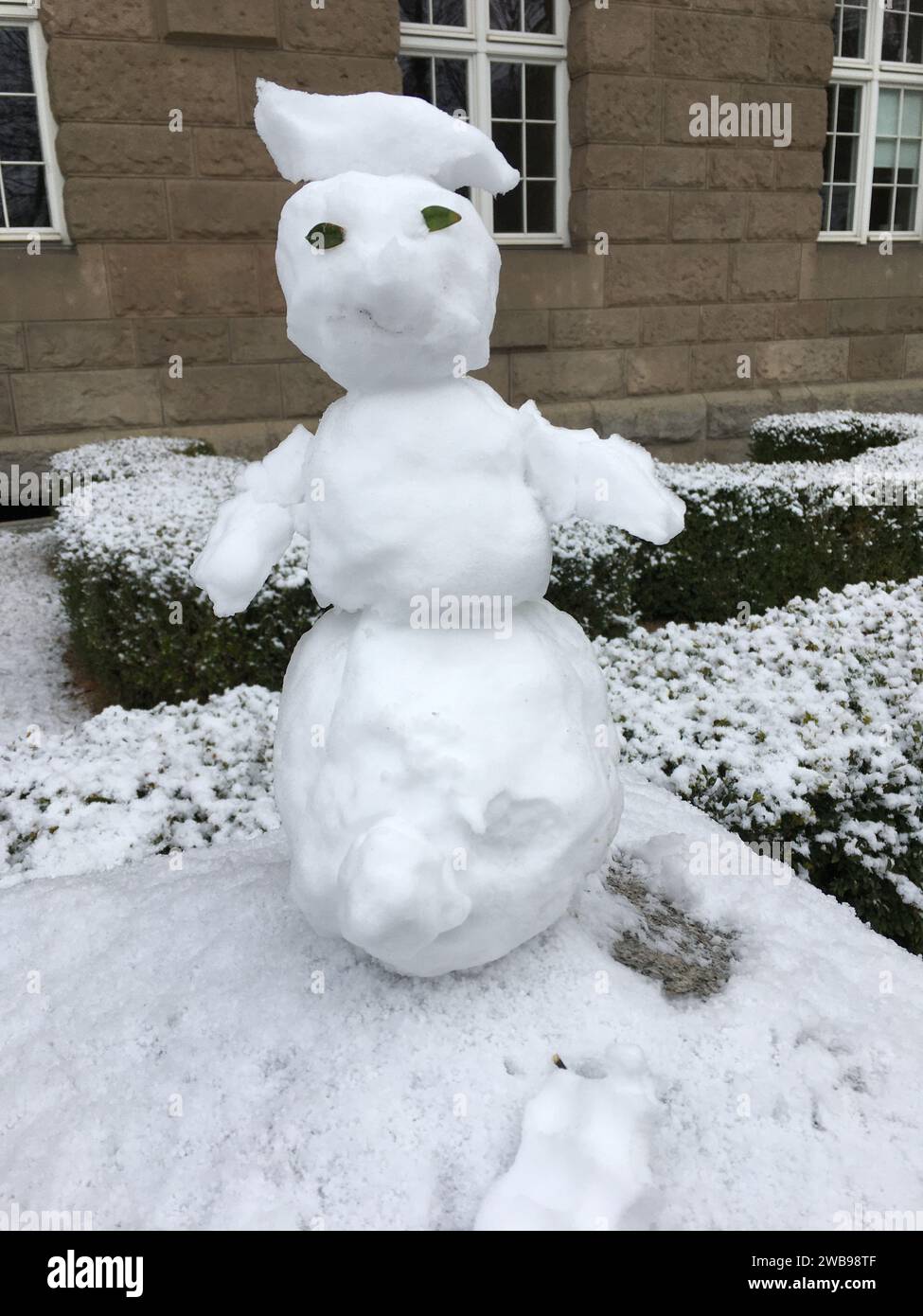 Un piccolo pupazzo di neve è migliorato su un palo di pietra. Versione mini. Inverno in Polonia. Foto Stock