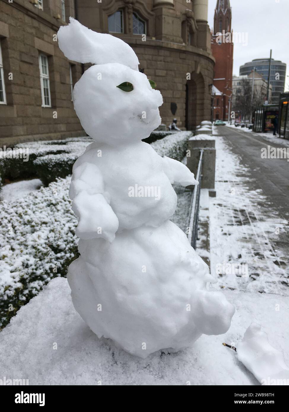 Un piccolo pupazzo di neve è migliorato su un palo di pietra. Versione mini. Inverno in Polonia. Foto Stock