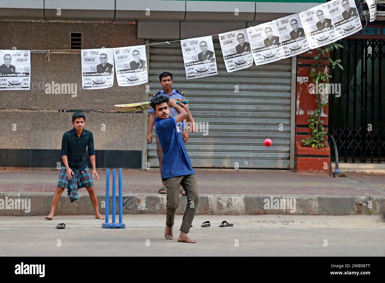 Un gruppo di giovani che giocano a cricket sul centro degli affari della città, Dilkusha Street, alla vigilia delle 2 ° elezioni parlamentari nazionali, Dhaka, Bangladesh, 7 gennaio Foto Stock