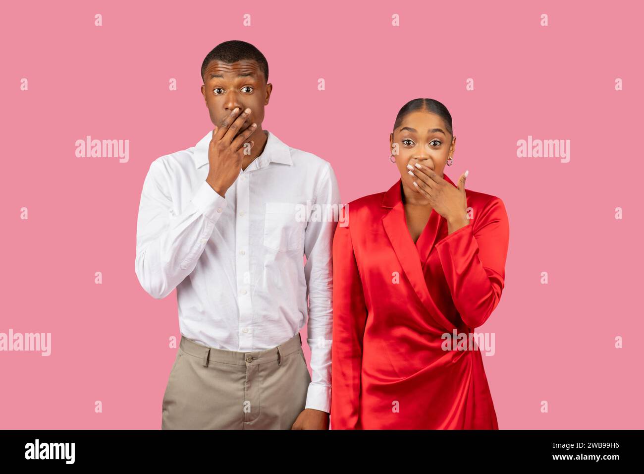 Uomo e donna neri scioccati che coprono le bocche, camicia bianca, vestito rosso Foto Stock