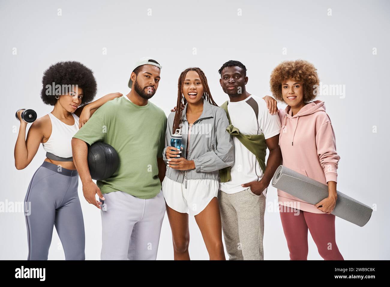 gruppo di giovani amici afroamericani in piedi con attrezzature sportive su sfondo grigio Foto Stock