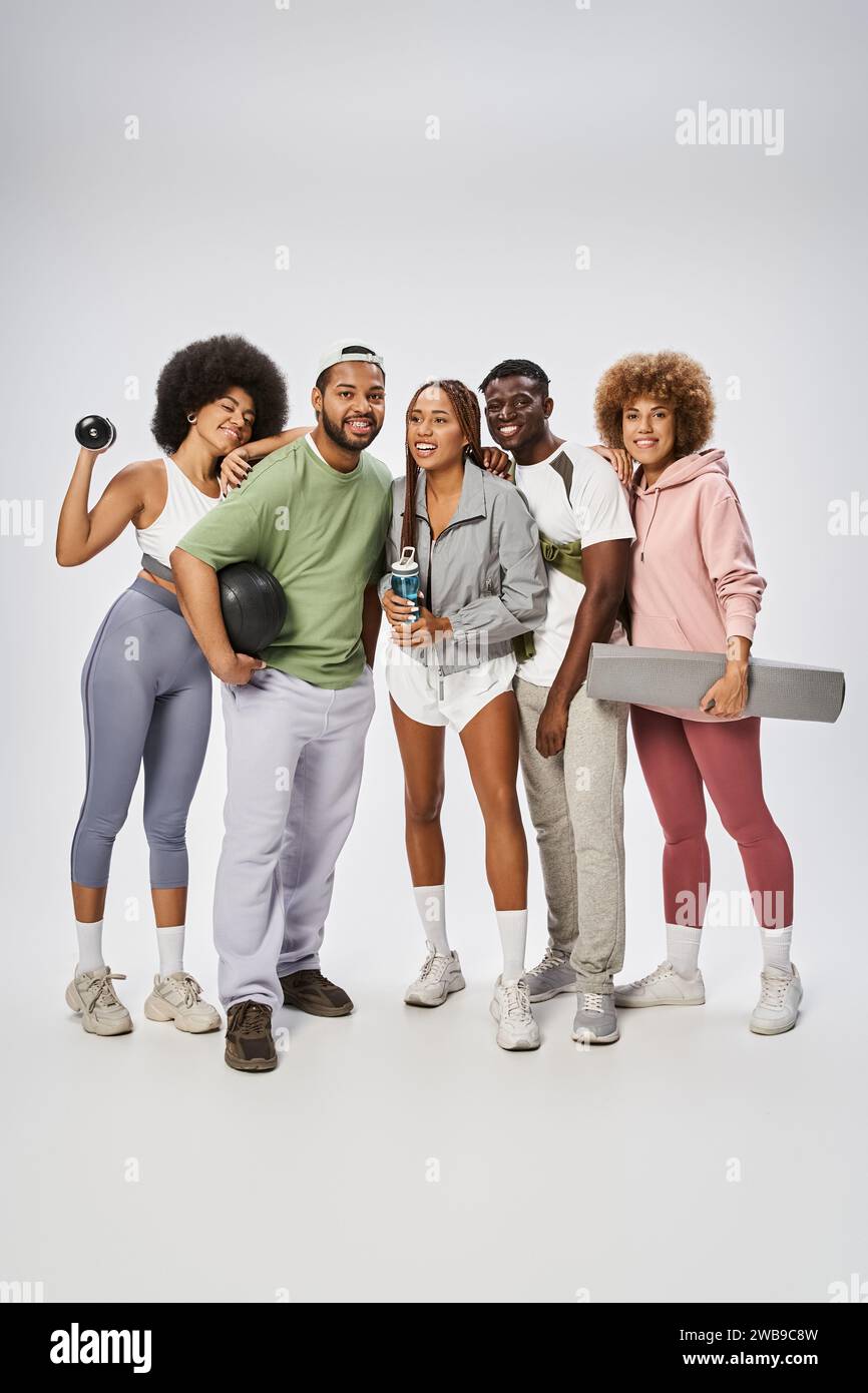 gruppo di amici afroamericani sportivi in piedi con attrezzature sportive su sfondo grigio Foto Stock