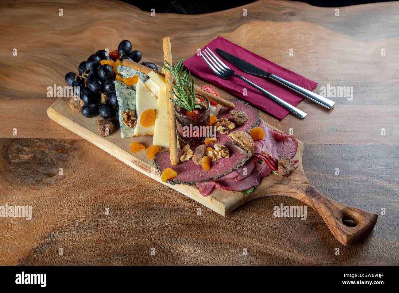 Piatto di antipasti con carne affumicata, formaggio cheddar e uva nera Foto Stock