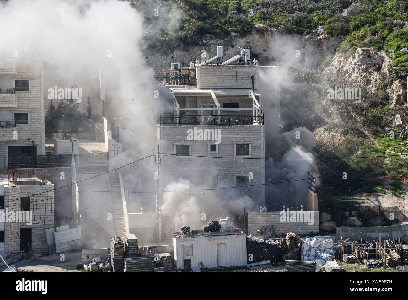 Gerusalemme, Israele. 9 gennaio 2024. Il fumo sale mentre le forze di sicurezza israeliane demoliscono la casa di due militanti di Hamas nel quartiere palestinese di Gerusalemme est di Sur Bahir. Su istruzioni del primo ministro israeliano Benjamin Netanyahu, due case appartenenti a due fratelli palestinesi, che presumibilmente hanno causato la morte di 3 israeliani in un attacco armato il 30 novembre, sono state distrutte. Le forze israeliane circondarono le case dei fratelli Murad e Ibrahim Nemr nella città di Sur Bahir e le fecero esplodere con una bomba. (Foto di Saeed Qaq/SOPA Images/Sipa USA) credito: SIPA USA/Alamy Live News Foto Stock