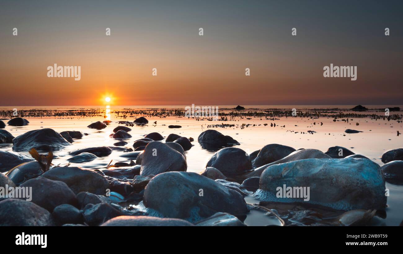 tramonto sul mare con grandi pietre Foto Stock