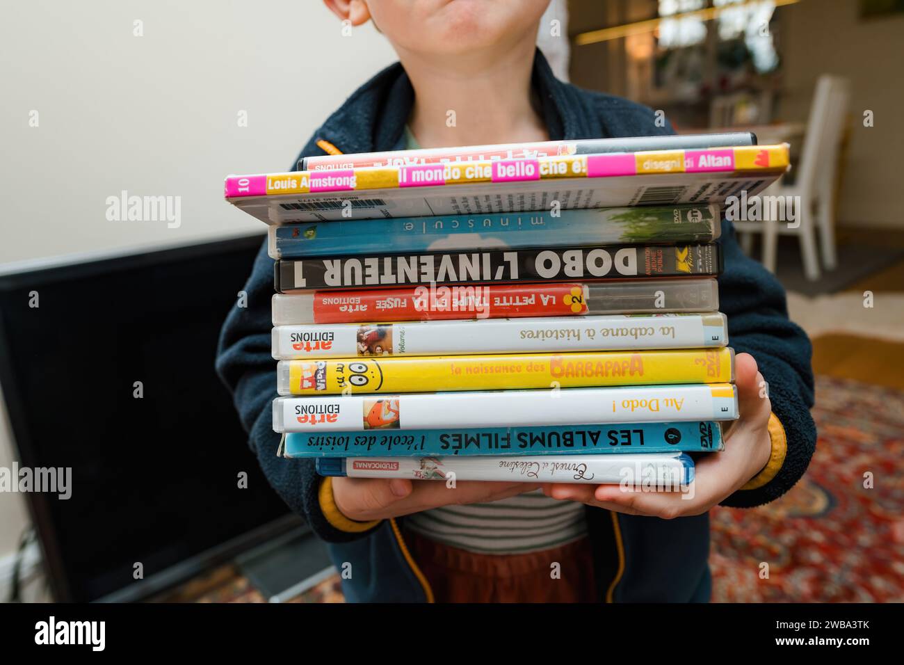 Parigi, Francia - 16 dicembre 2023: Una mano mostra il DVD la petite Taupe accanto ai piedi di un bambino, una serie di cartoni animati ceca molto amata Foto Stock