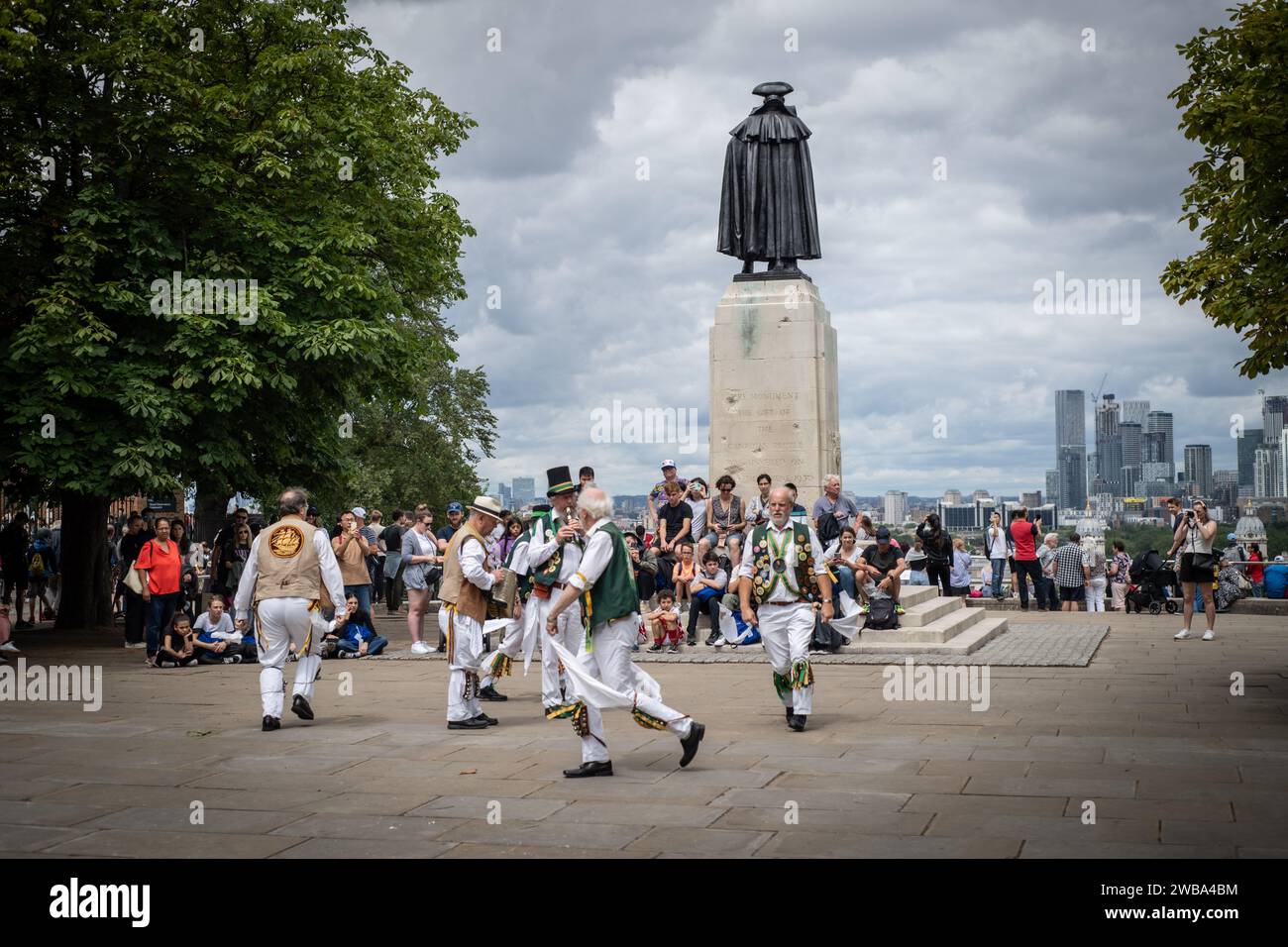 Morris men che ballano nel Greeenwich Park di fronte al Wolfe Staute, affacciato su Londra e Canary Wharf Foto Stock