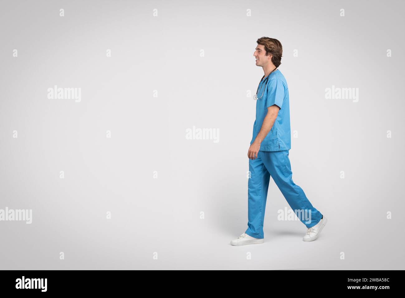 Medico maschile in scrub camminare, vista laterale Foto Stock