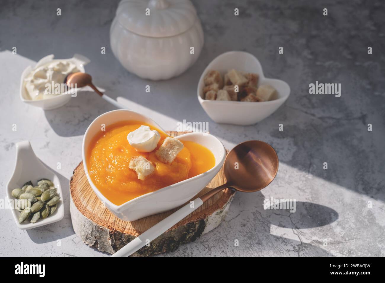 Zuppa di zucca in purea con semi di sesamo e semi di zucca in un piatto a forma di cuore. Zuppa vegana per tutte le stagioni. Foto Stock