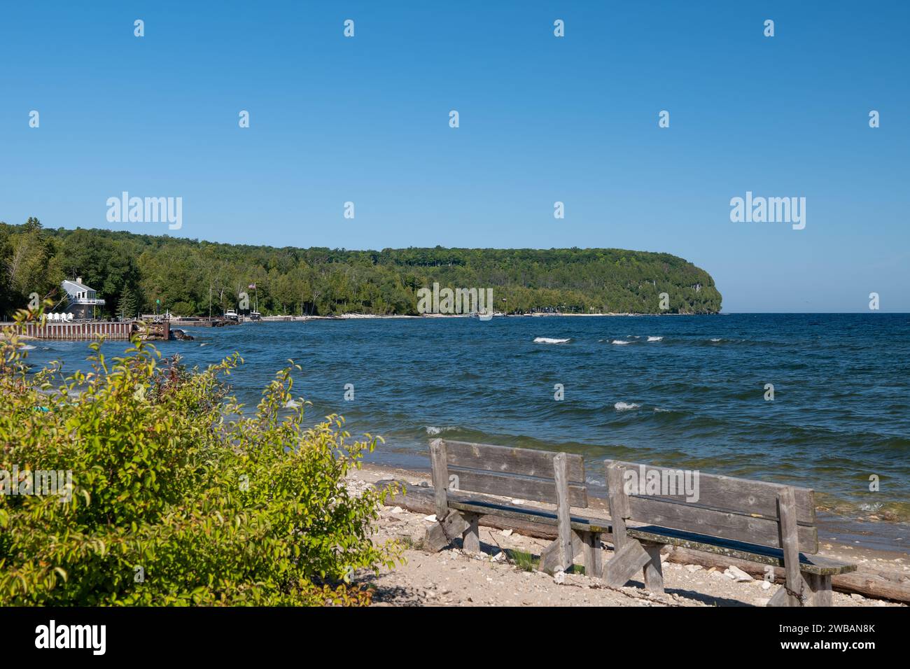 Panchine di legno sulla spiaggia sulla riva di un bellissimo lago in una giornata di sole con cielo azzurro. Foto Stock