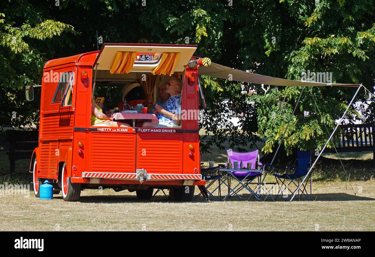Coppia che ha fatto un picnic in un pulmino rosso classico restaurato Citroën tipo H nelle giornate di sole. Foto Stock