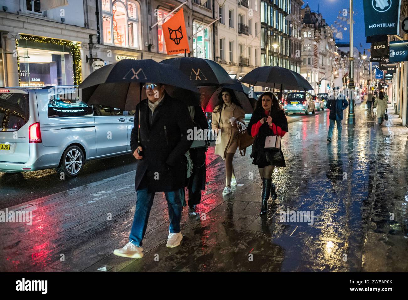 Gli amanti dello shopping affrontano il freddo inverno durante le fredde nevi e le docce a pioggia in Old Bond Street, l'etichetta di lusso di Londra Street, Inghilterra, Regno Unito Foto Stock