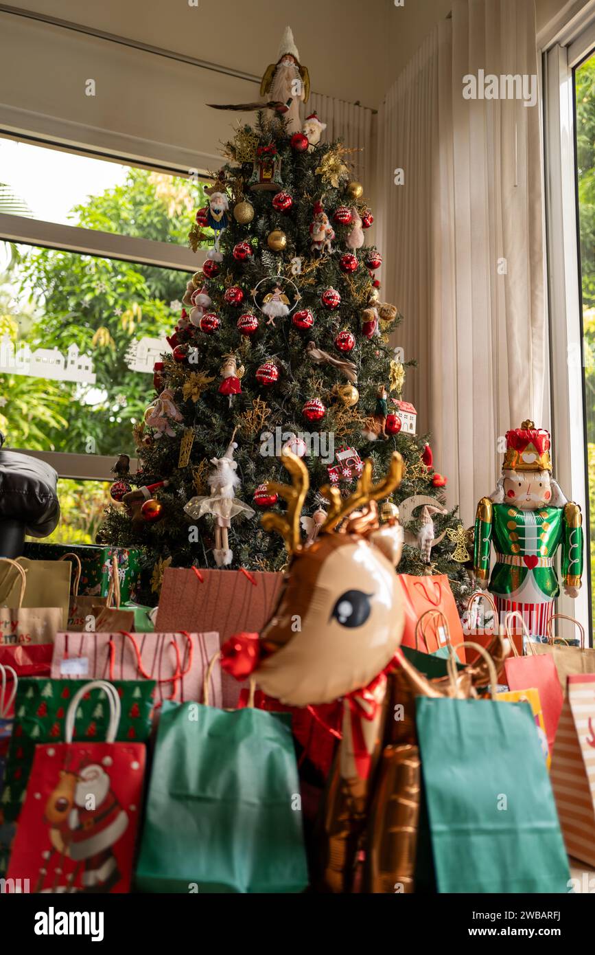 Un animale festoso accanto a una pila di regali sullo sfondo di un albero di Natale Foto Stock
