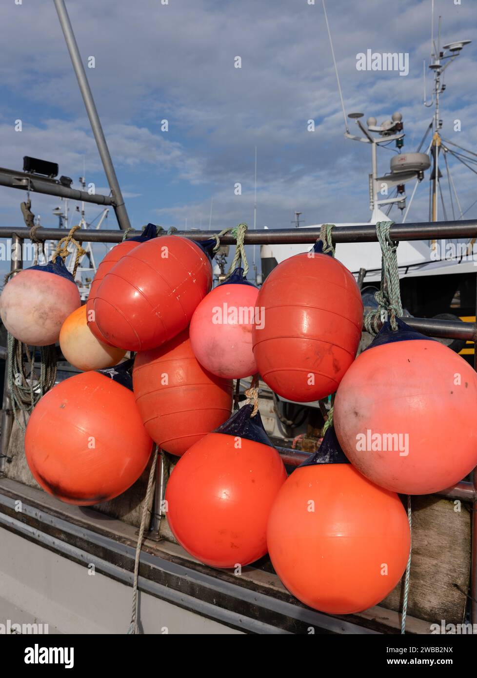Primo piano di una massa di parafanghi per la pesca arancioni attaccati alla barca. Foto Stock