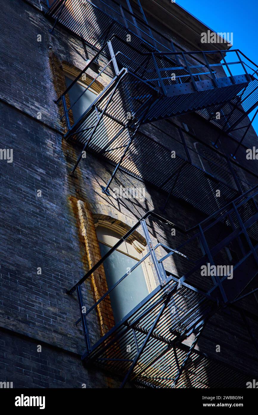 Ombre geometriche Urban Fire Escape sulla facciata in mattoni Foto Stock