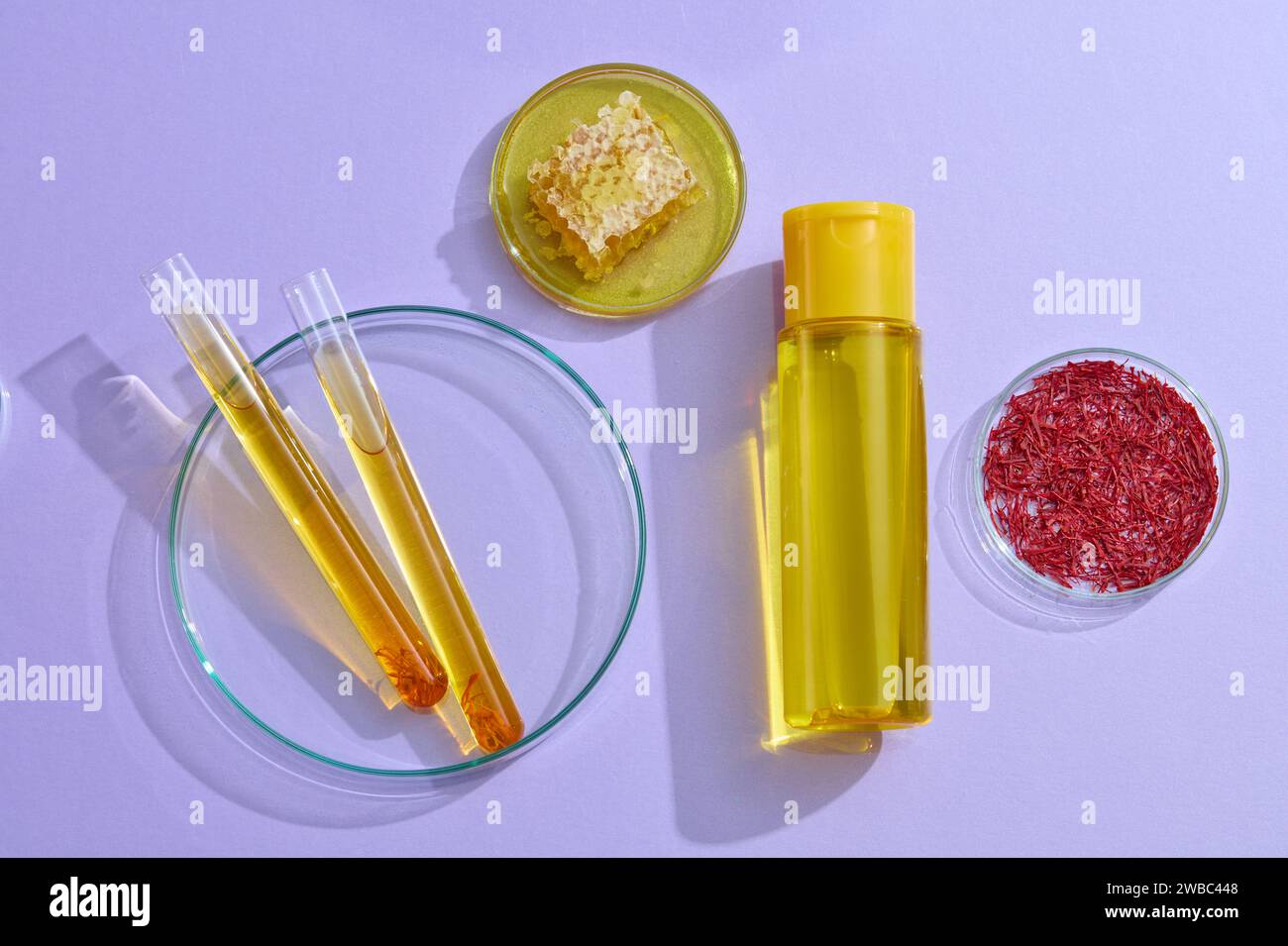 Foto pubblicitaria per cosmetici estratti da zafferano e miele con concetto di laboratorio. Un mockup cosmetico giallo decorato con zaffr Foto Stock