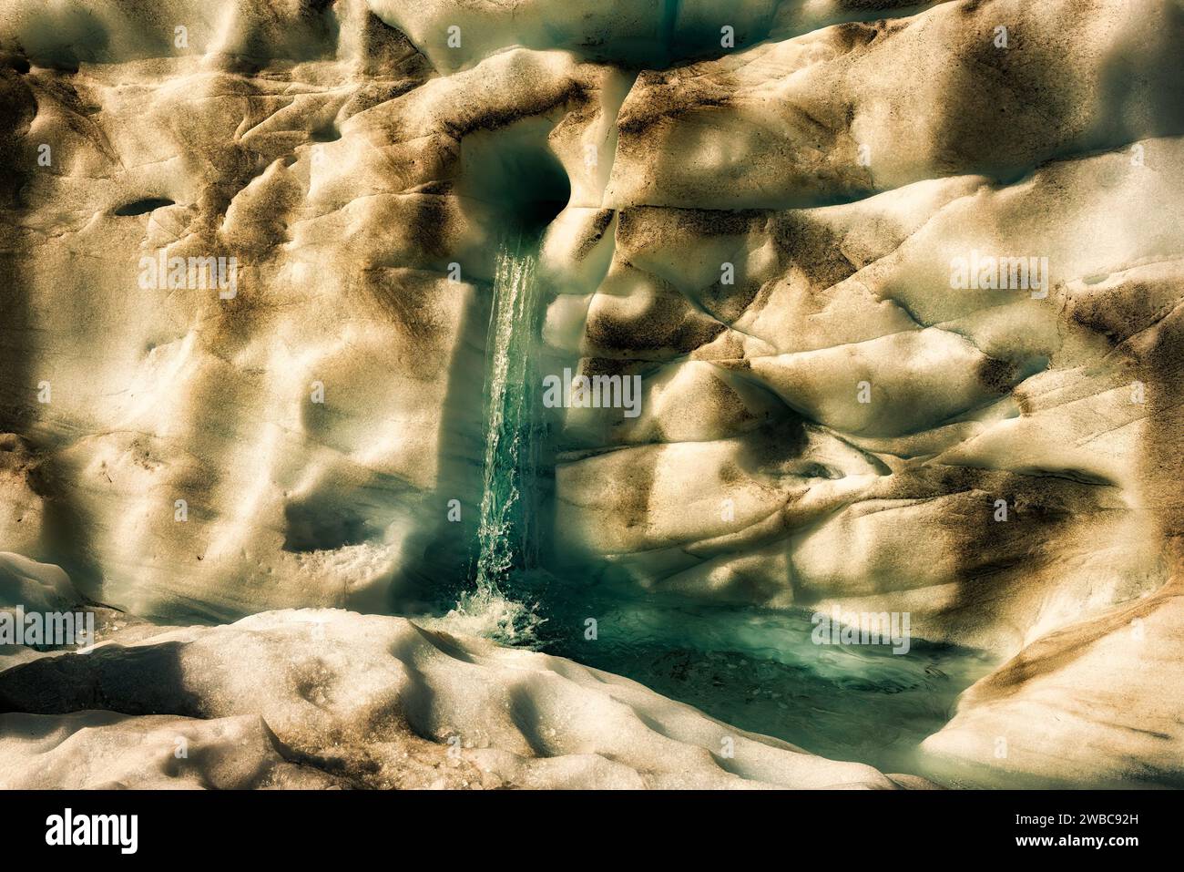 L'acqua sciolta esce da un piccolo tunnel sul fondo ghiacciato del Ghiacciaio Fox nelle alpi meridionali Foto Stock