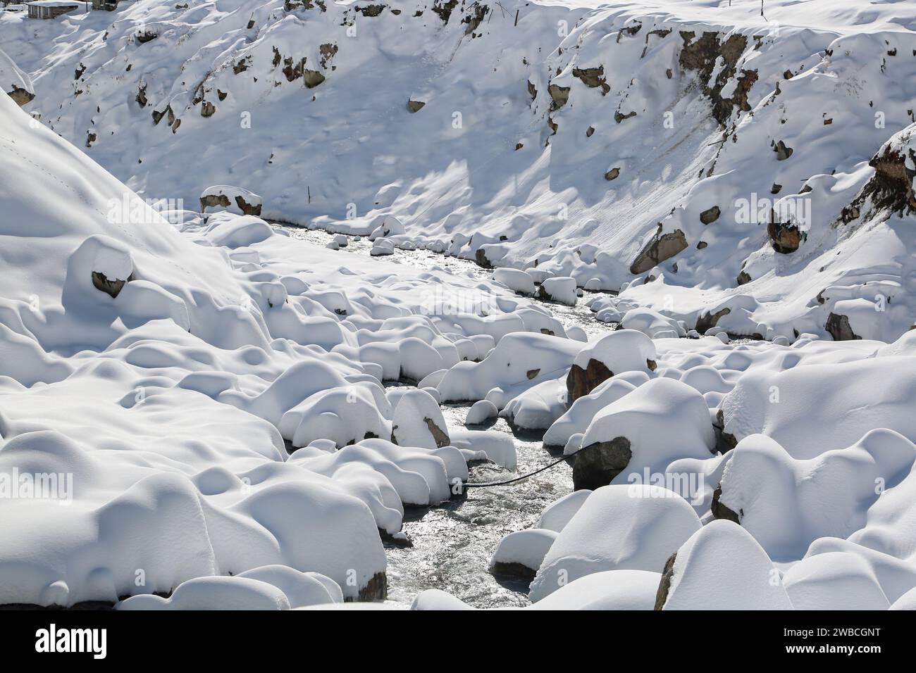 Riva del fiume coperta di neve e pietre in Himalaya. Punteggiata da lunghe catene montuose e scintillanti gioielli nella mappa del mondo, Uttarakhand è famosa per questo Foto Stock