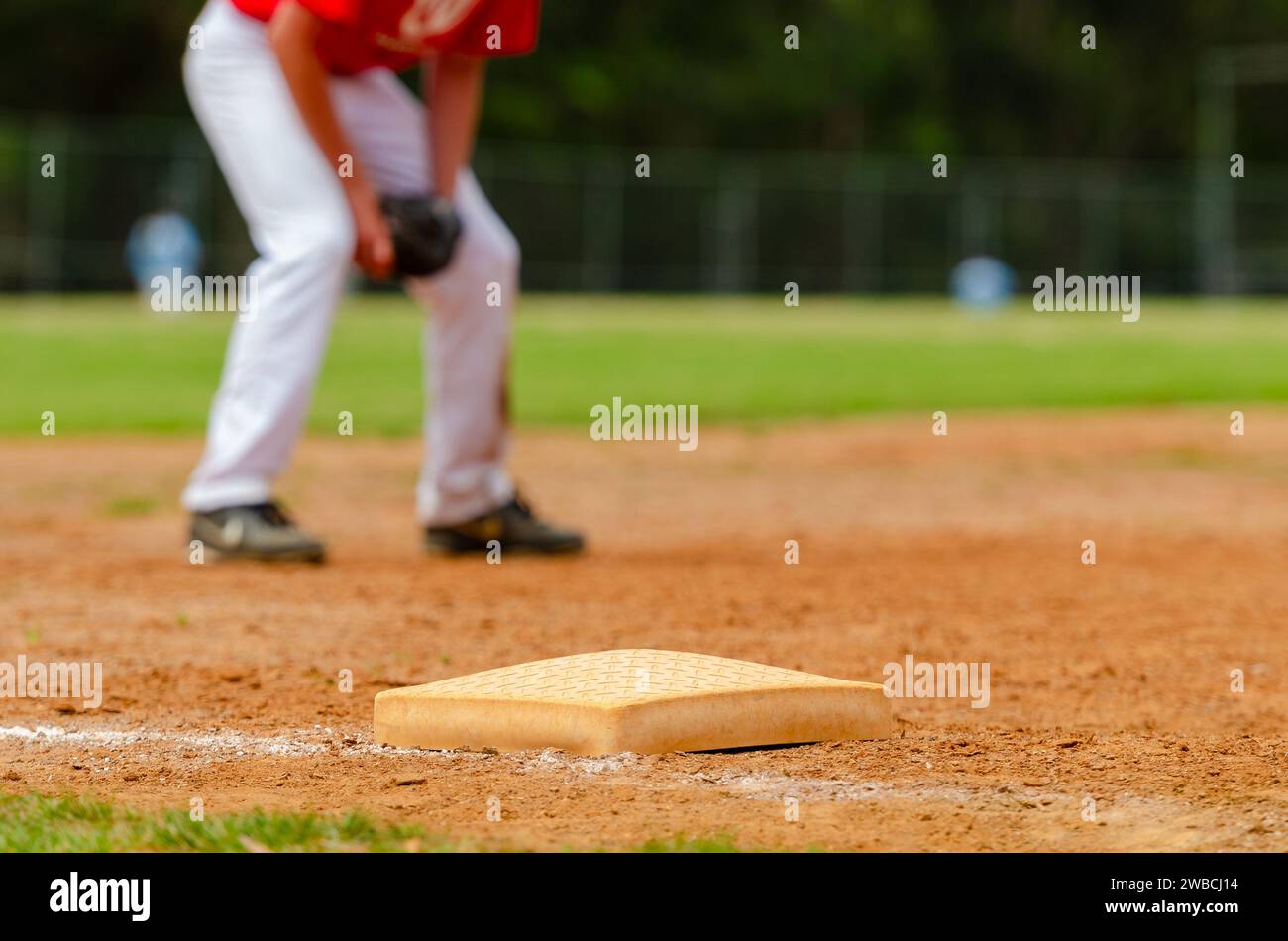 Primo piano della terza base di baseball e una linea di foul con campo di erba sullo sfondo. Primo piano sul campo da baseball. Foto Stock