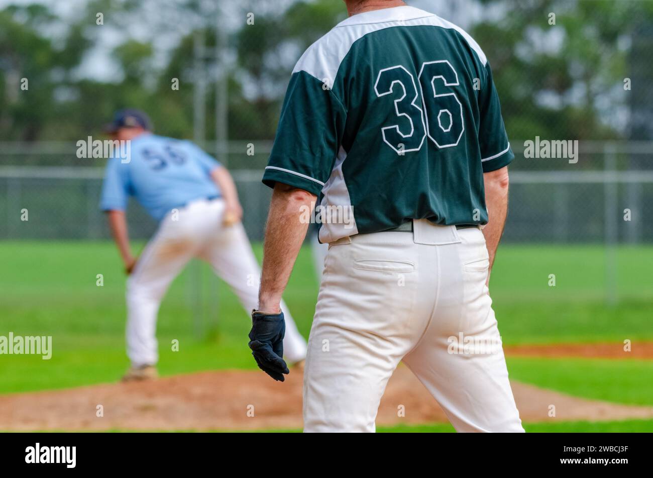 Partita di baseball, il corridore della prima base sta guardando il lanciatore e si sta preparando a rubare la seconda base. Foto Stock